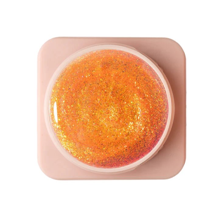 Trendy nagelproducten in een pot met oranje glitters voor een sprankelende manicure