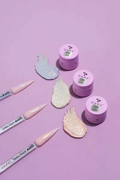DNKa Jewel Paste in verschillende kleuren weergegeven met applicators en potjes op een paarse achtergrond