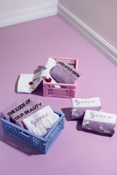 DNKa sokken in verschillende kleuren, gepresenteerd in mandjes op een paarse vloer